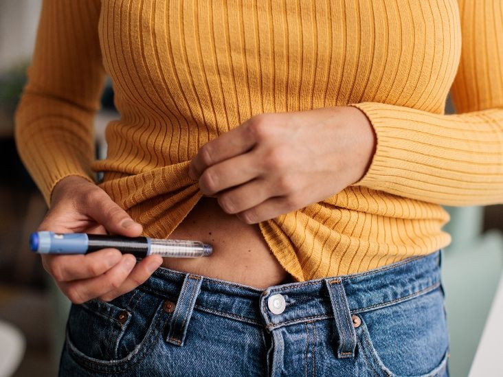A person holding an injection pen near their abdomen