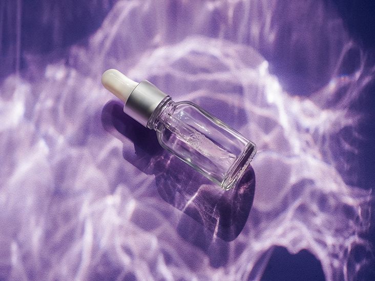 A glass dropper bottle on a purple background