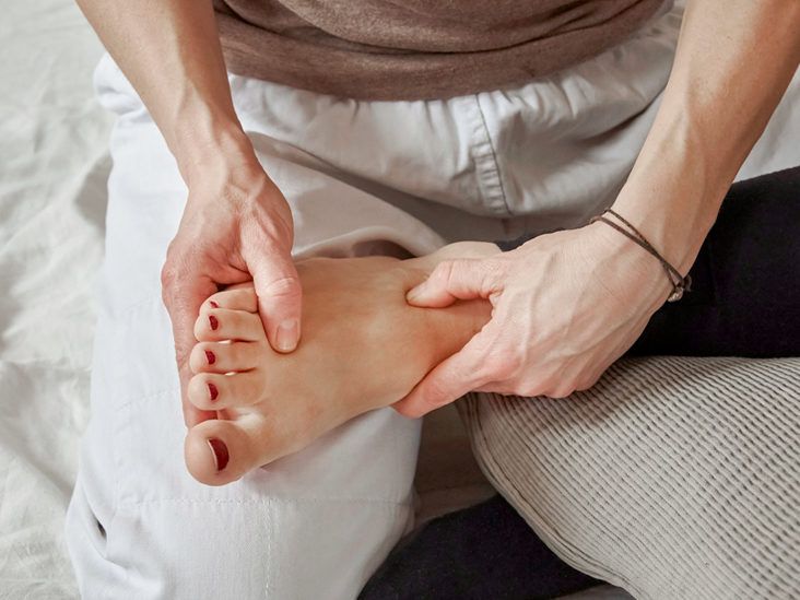 A person applying pressure to points on another person's foot