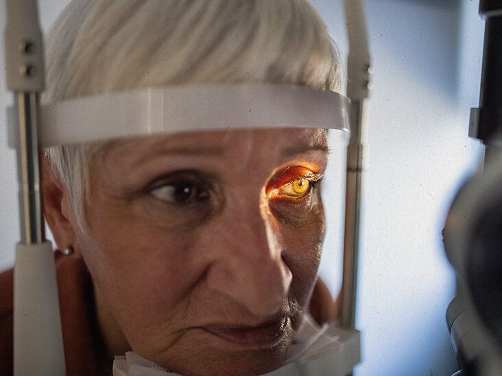 An older adult having an eye exam at a slit lamp