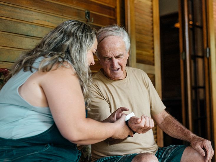 An adult checking an older family member's blood pressure at home