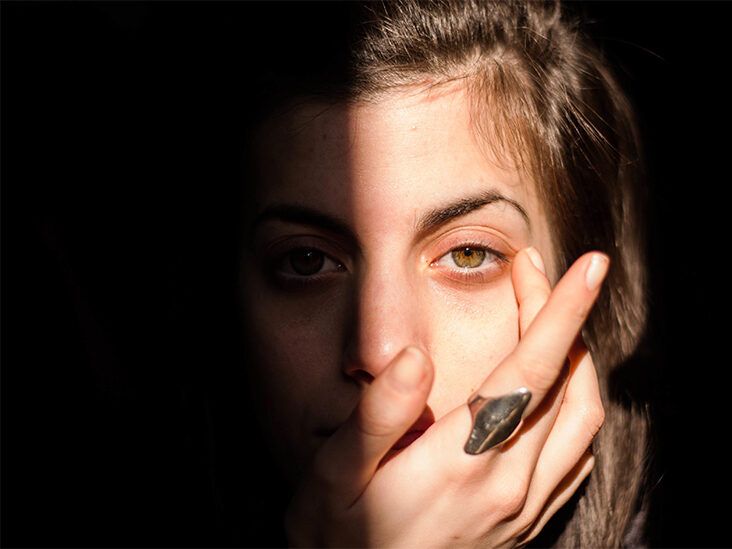 A person in sunlight touching the skin beneath one eye