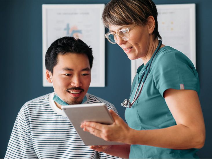 A nurse reviewing information on a tablet with a patient
