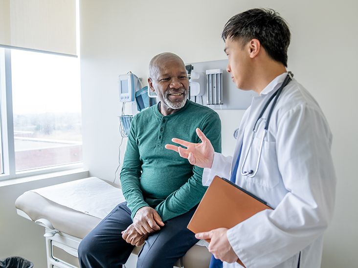 An older adult talking with a doctor in an exam room