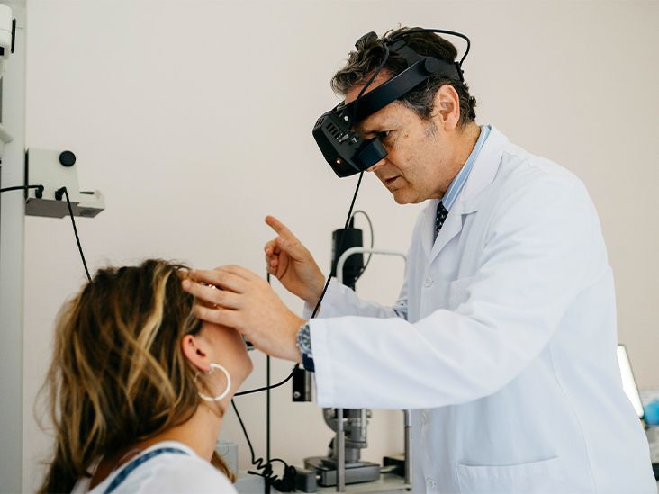 An eye doctor examining a person's eyes in an exam room