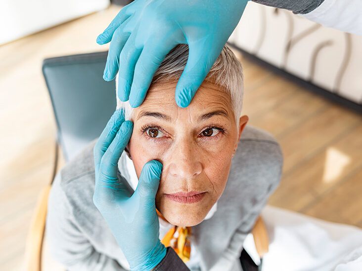 An eye doctor in gloves examining an older adult's eyes